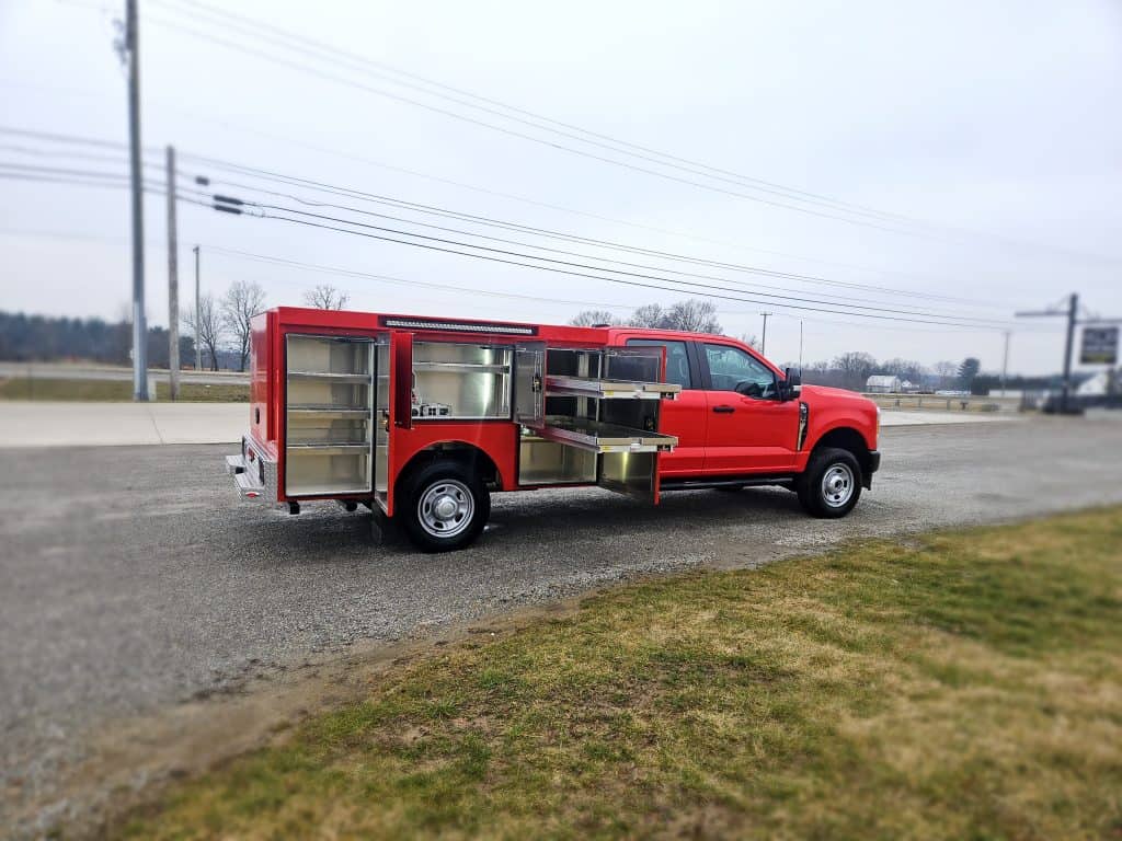 Red fire department truck with a custom service body installed by ALE Truck Beds in Dalton, Ohio, featuring open compartments for firefighting equipment.