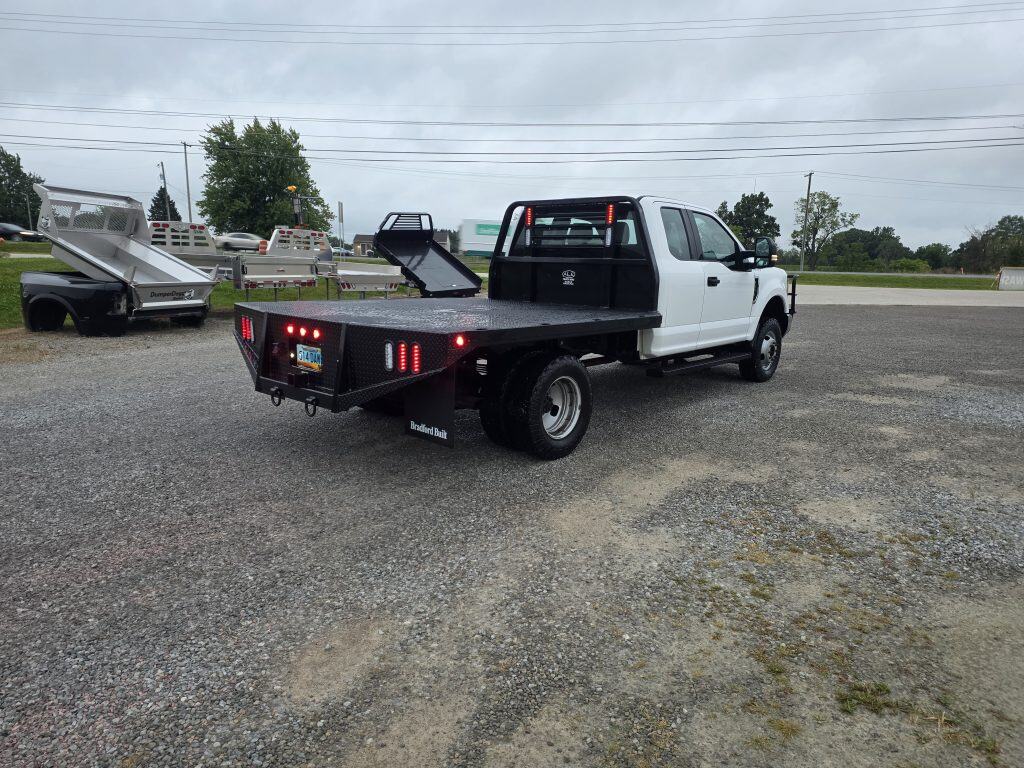 White work truck with a black Bradford Built flatbed installed by ALE Truck Beds in Dalton, Ohio, featuring a steel headache rack and integrated lights.